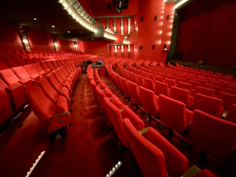 Side view of empty seats in a theater red velvet look partially showing closed red curtains