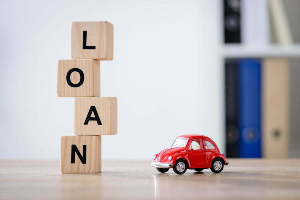 wooden cubes with loan lettering and red toy car on wooden tabletop surface